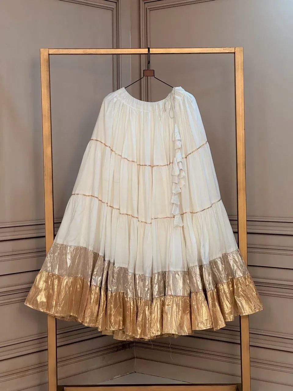 Off-white rayon lehenga with lampi lace and gold frill on display hanger