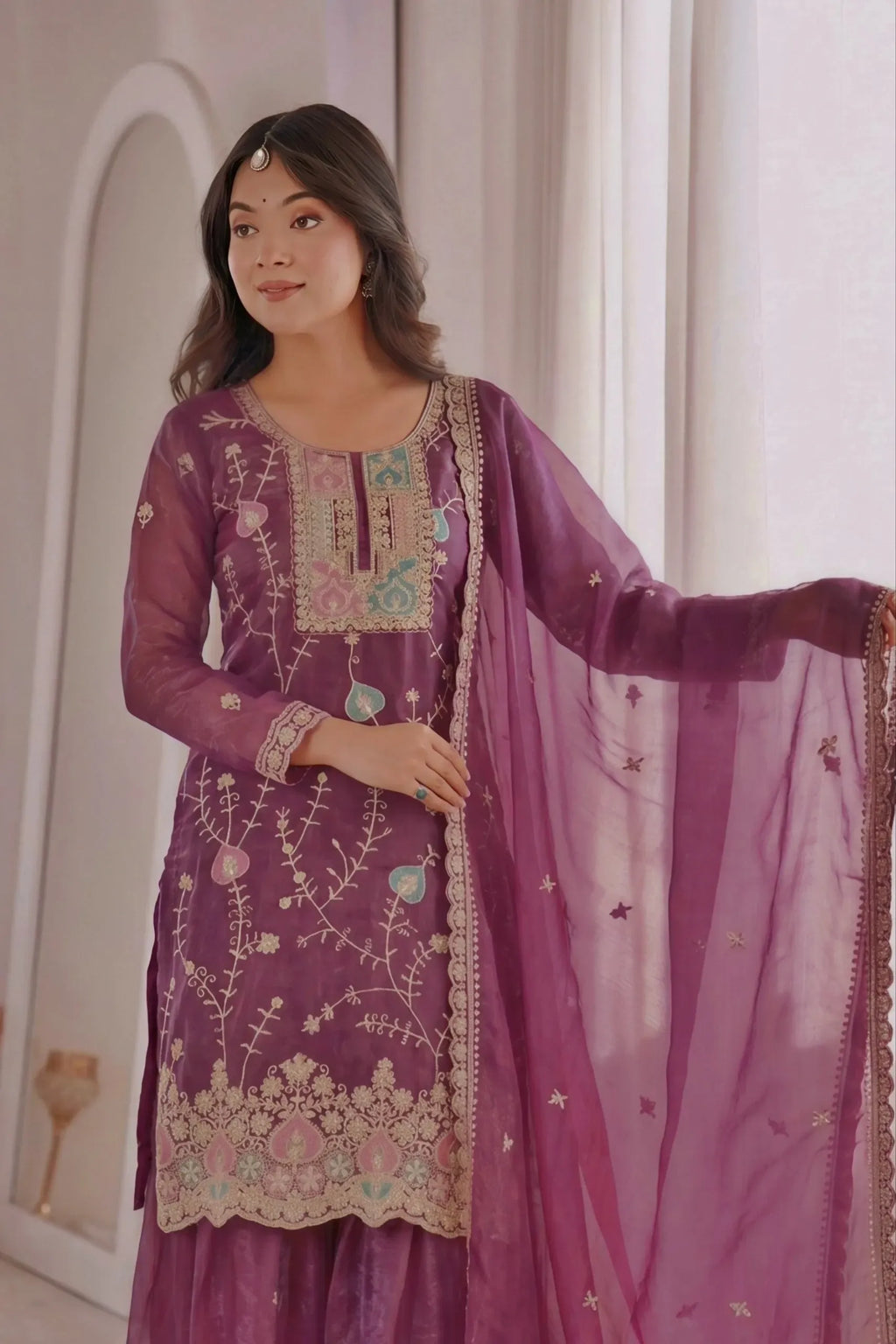 Model wearing a purple fendy silk suit holding the edge of the embroidered dupatta