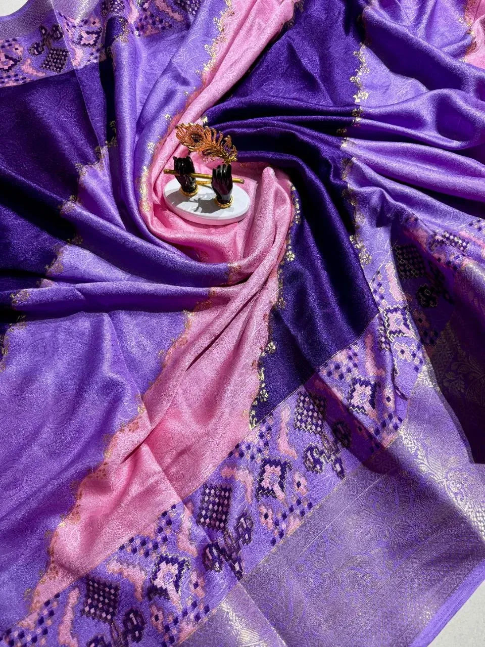 Purple and pink georgette saree folded in circular pattern with decorative flute