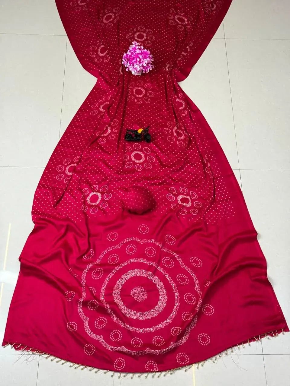 Red georgette saree laid flat with intricate print and pallu tassels