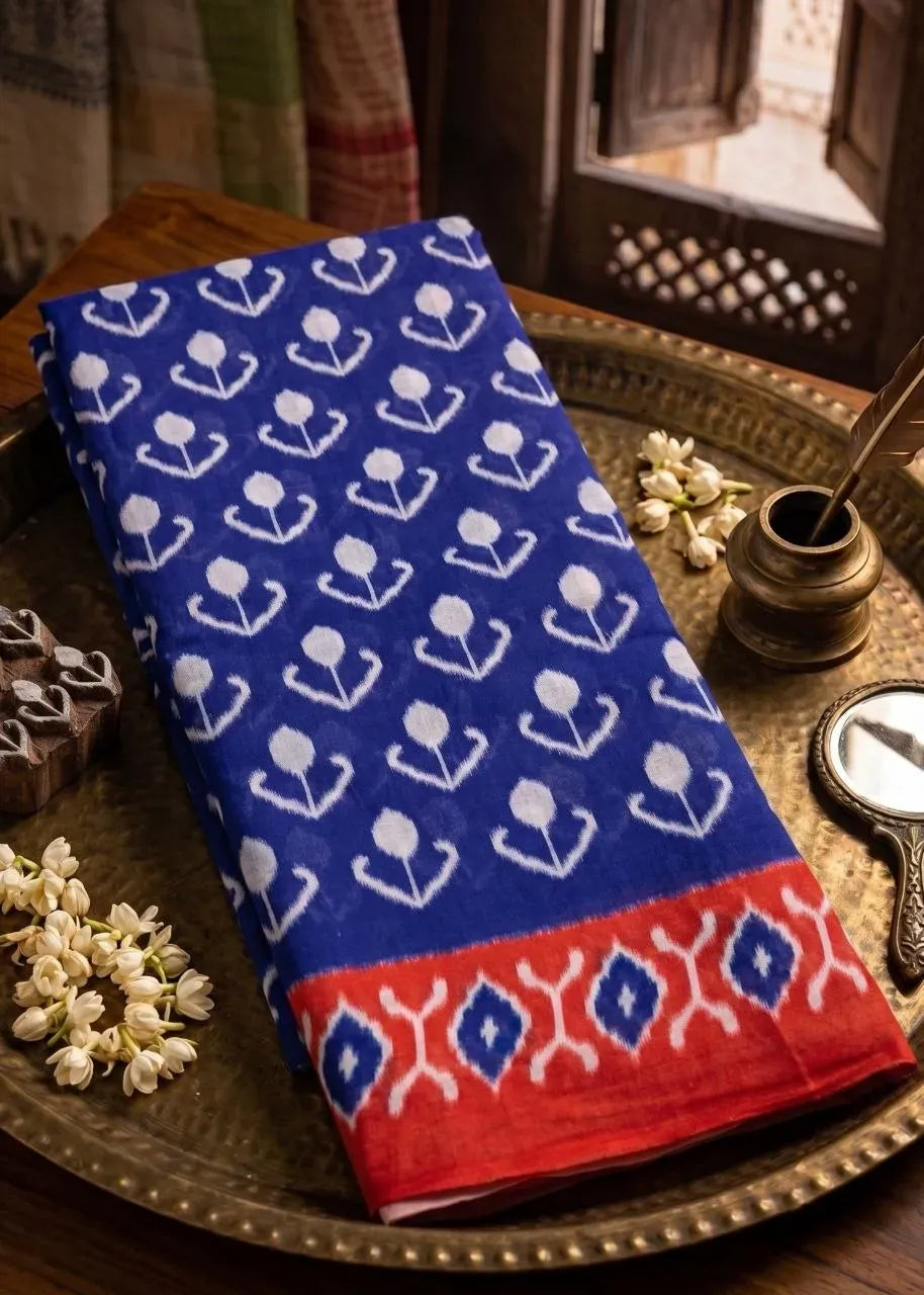Folded royal blue pure cotton saree with white block print and red border on brass tray