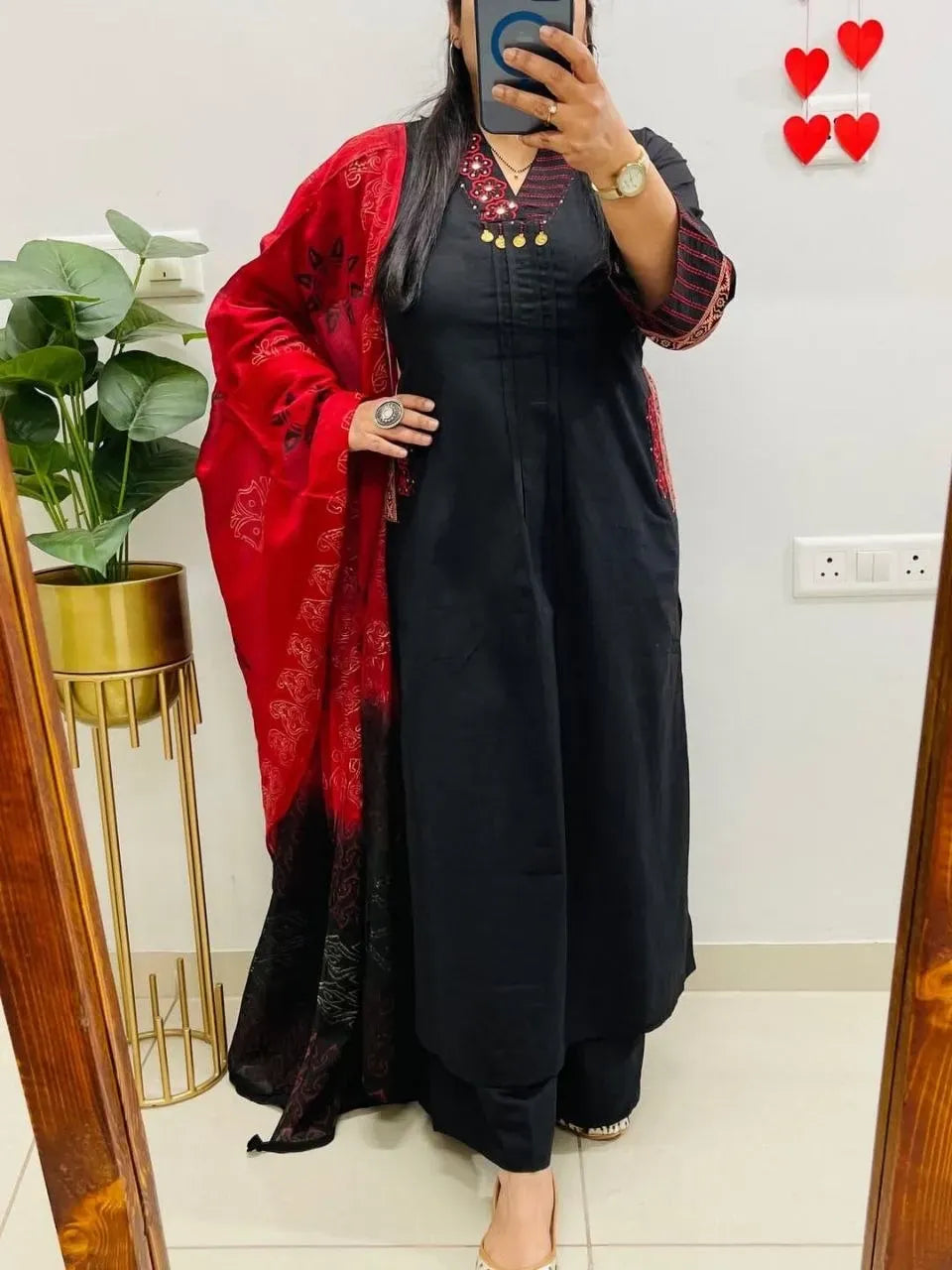Model wearing black pure cotton suit set with red dupatta posing in front of mirror