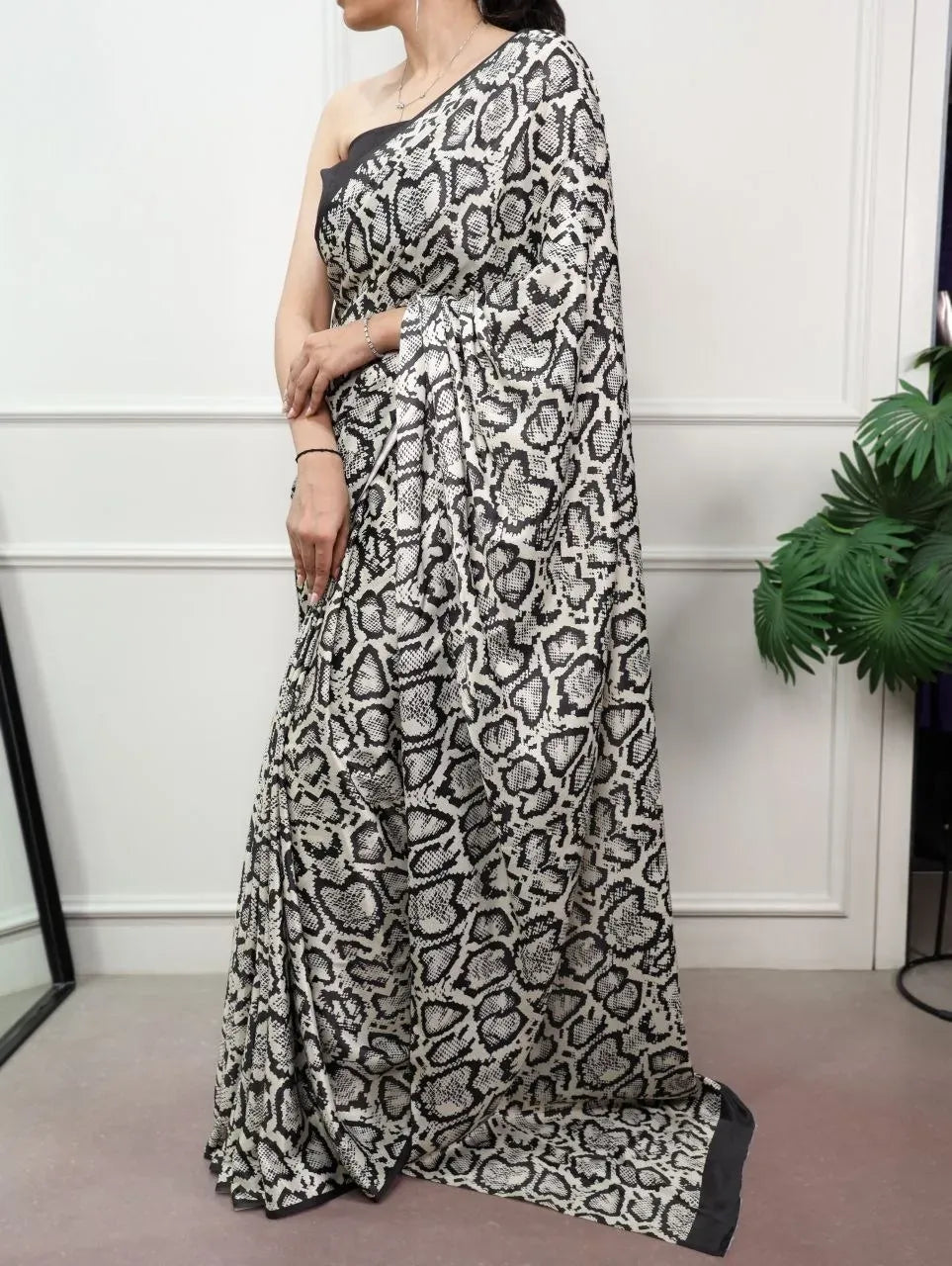 Model wearing black and white printed satin silk saree standing front view