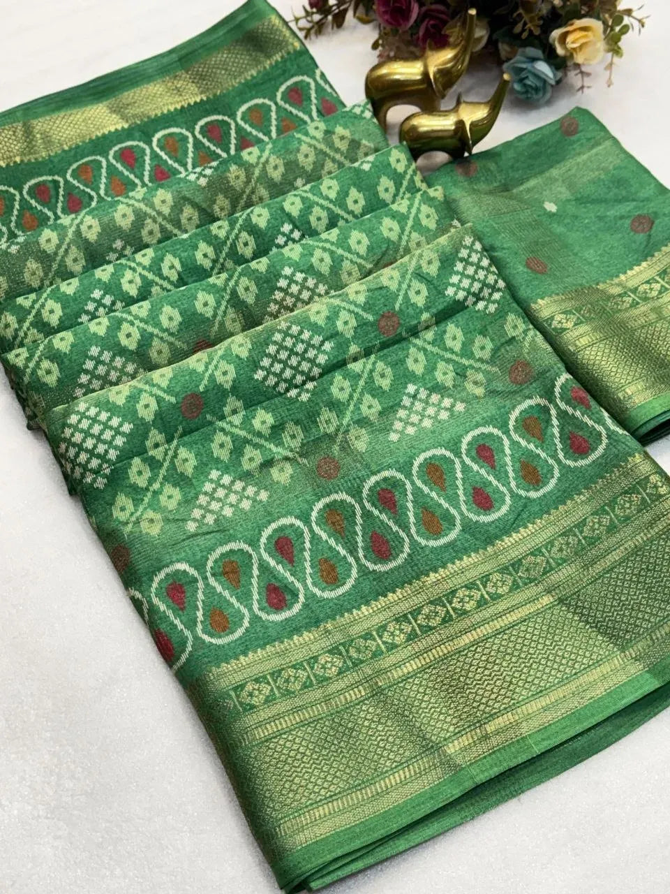 Green soft cotton saree with heavy jacquard border and ikkat print folded neatly