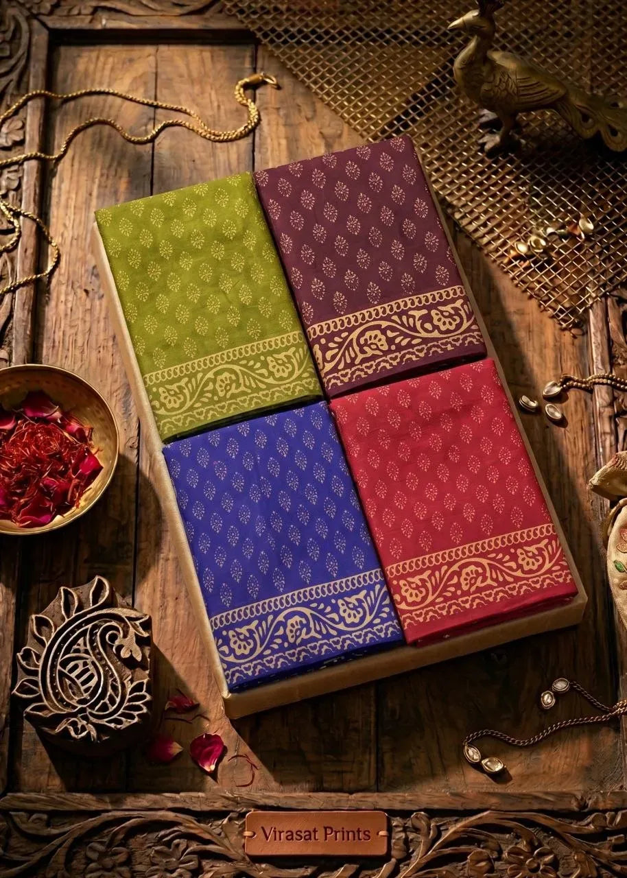 Four folded soft cotton sarees in green, wine, blue, and red with golden motifs