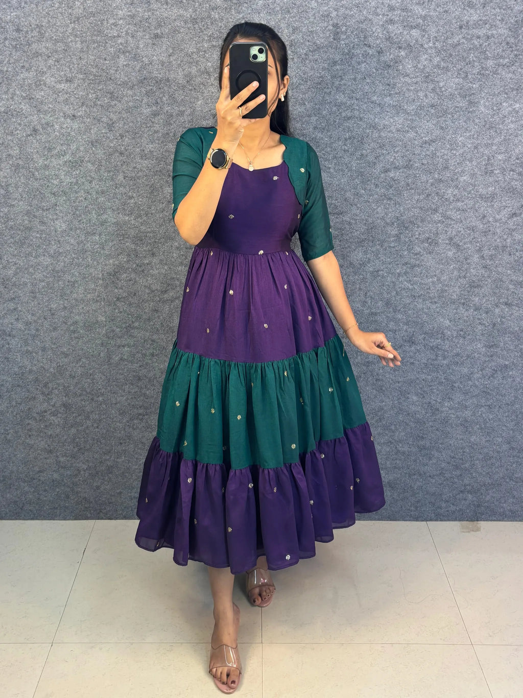 Woman posing in purple and green tiered blooming vichitra silk maxi gown with gold embroidery