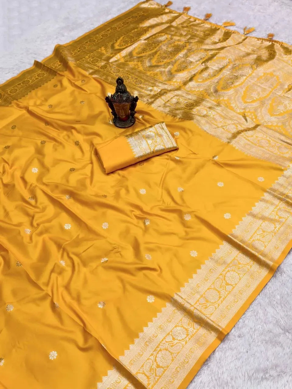 Yellow banarasi silk saree flat lay with gold zari pallu and blouse piece