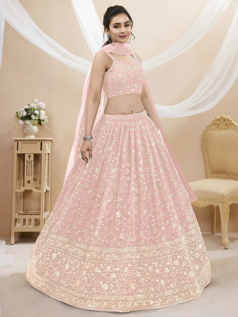 Model wearing a blush pink georgette lehenga with floral zari embroidery and sheer dupatta