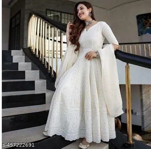 Full body view of woman posing on staircase wearing white chikankari gown