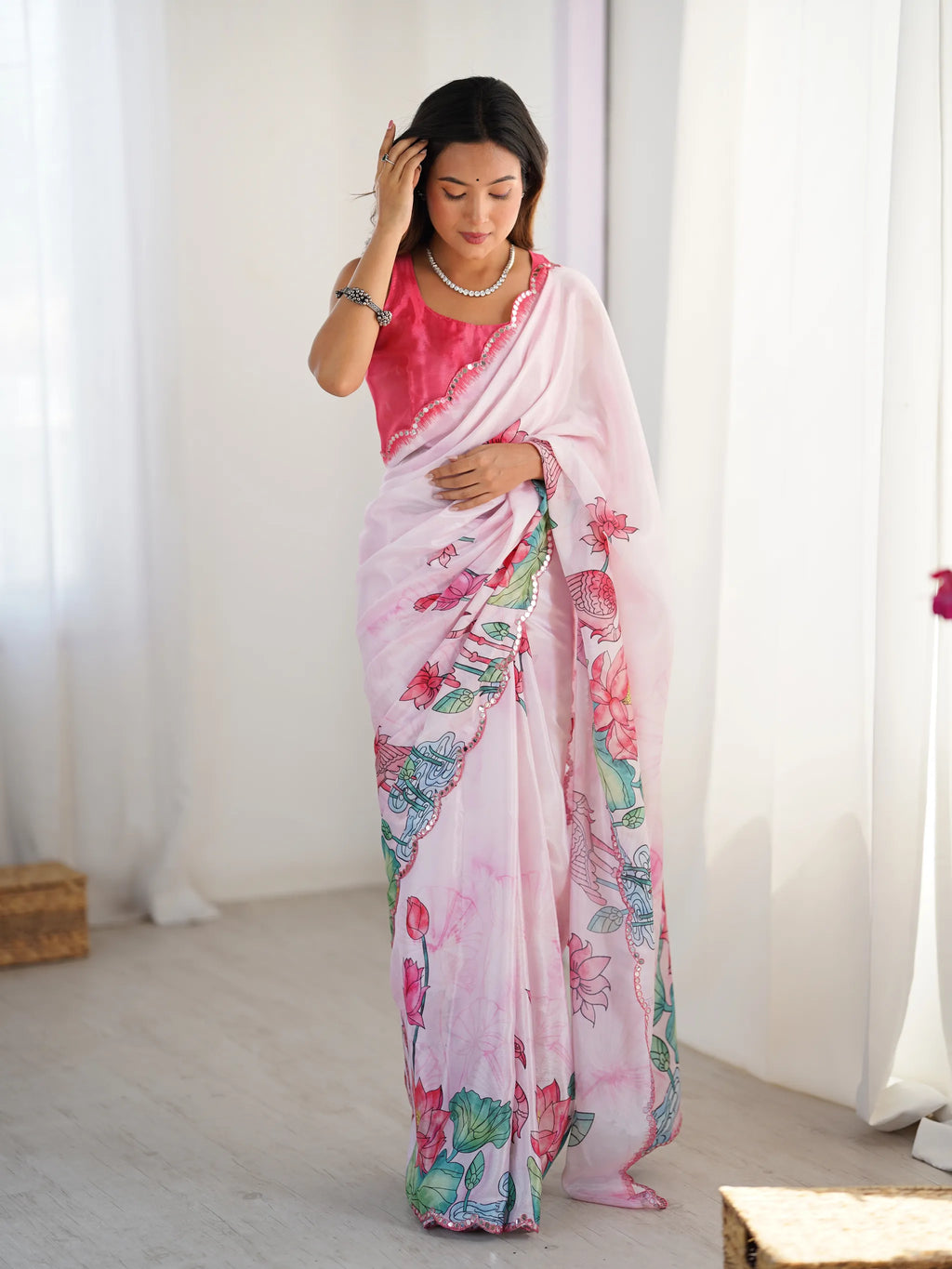 Model wearing pink floral print chinnon saree adjusting her hair