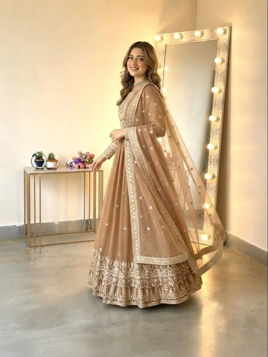 Model wearing beige georgette embroidered gown standing near mirror