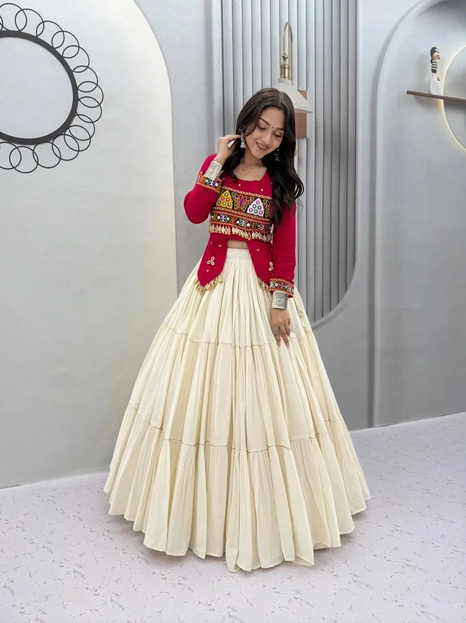 Model wearing bright pink embroidered top with cream tiered lehenga skirt