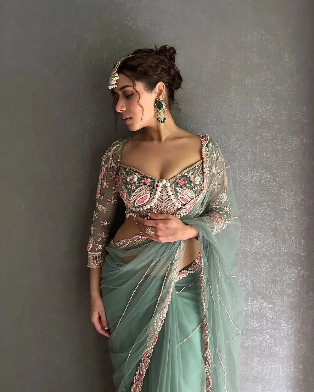 Model wearing mint green embroidered net saree with heavy work blouse