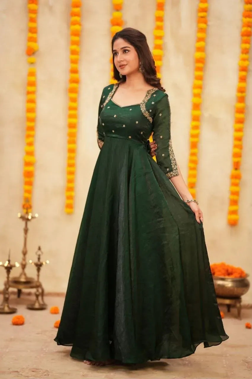 Full body view of model in emerald green ethnic gown against floral backdrop