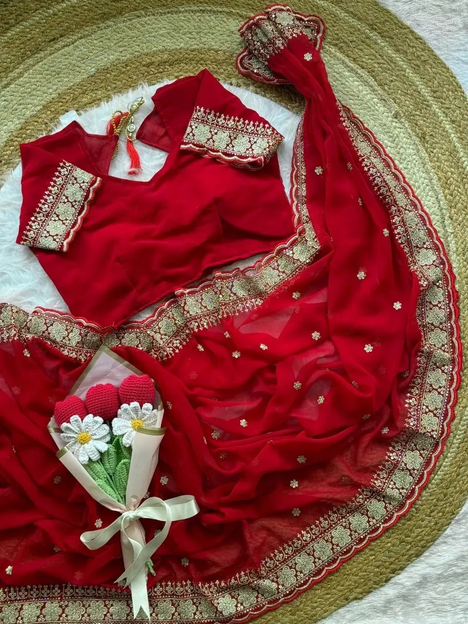 Red faux georgette saree with scalloped border and matching blouse displayed on round mat