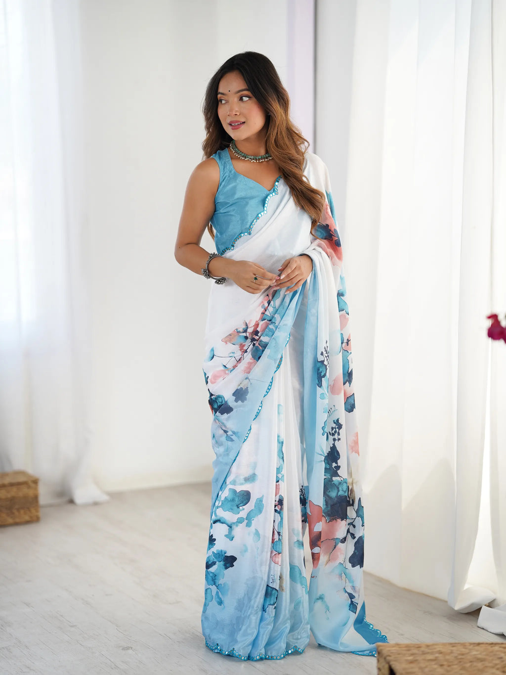 Model wearing white and blue floral print chinnon saree with blue sleeveless blouse