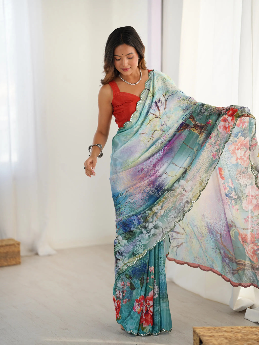 Model wearing heavy chinnon printed saree with mirror work lace border holding pallu