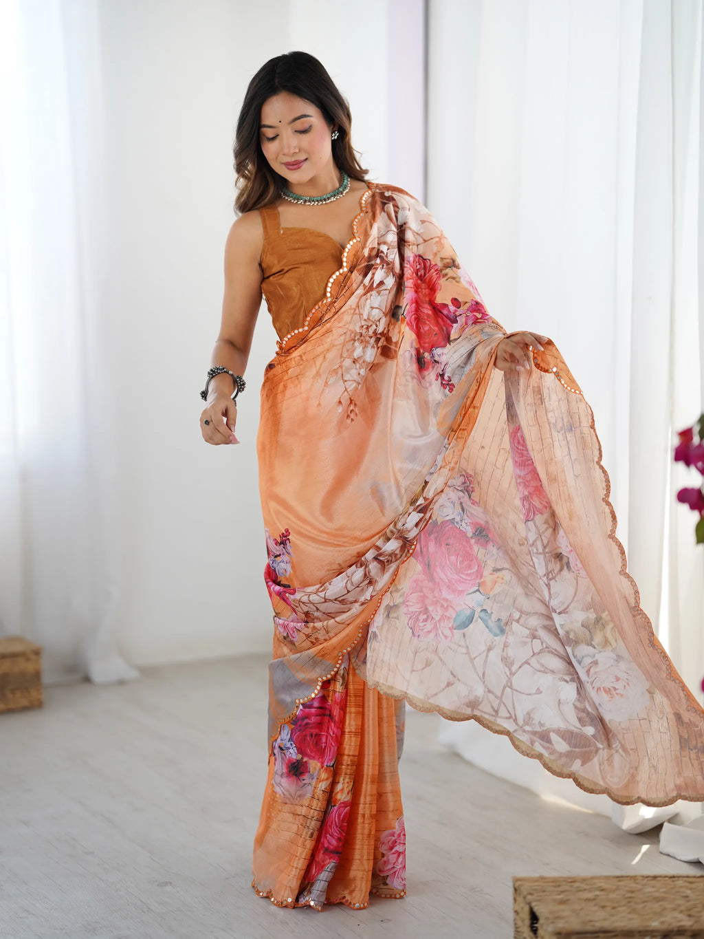 Model wearing orange floral print chinnon saree with mirror lace border