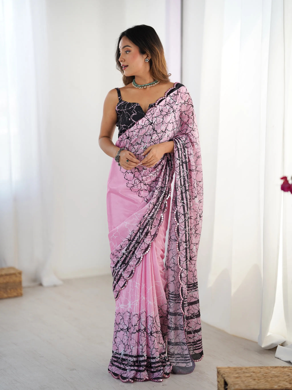 Model wearing pink printed chinnon saree with black and white motifs