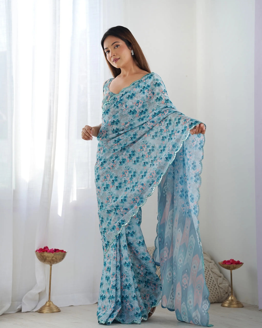 Full view of woman in blue festive chinnon saree holding pallu