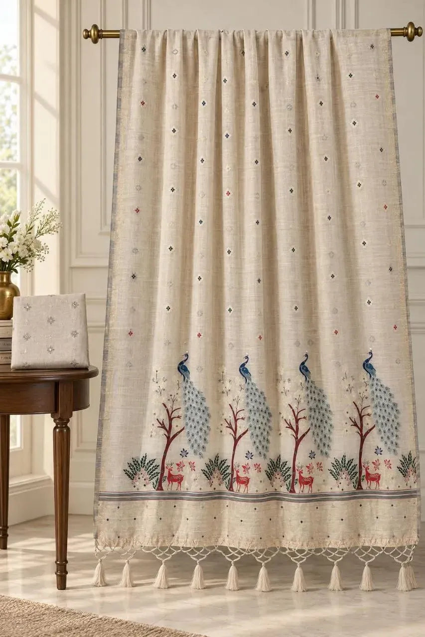 Beige Kalyani cotton saree with peacock and deer motifs displayed on a rod