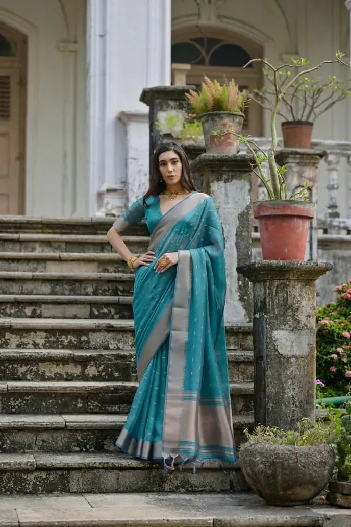 Front facing view of woman in teal blue soft silk saree on outdoor steps