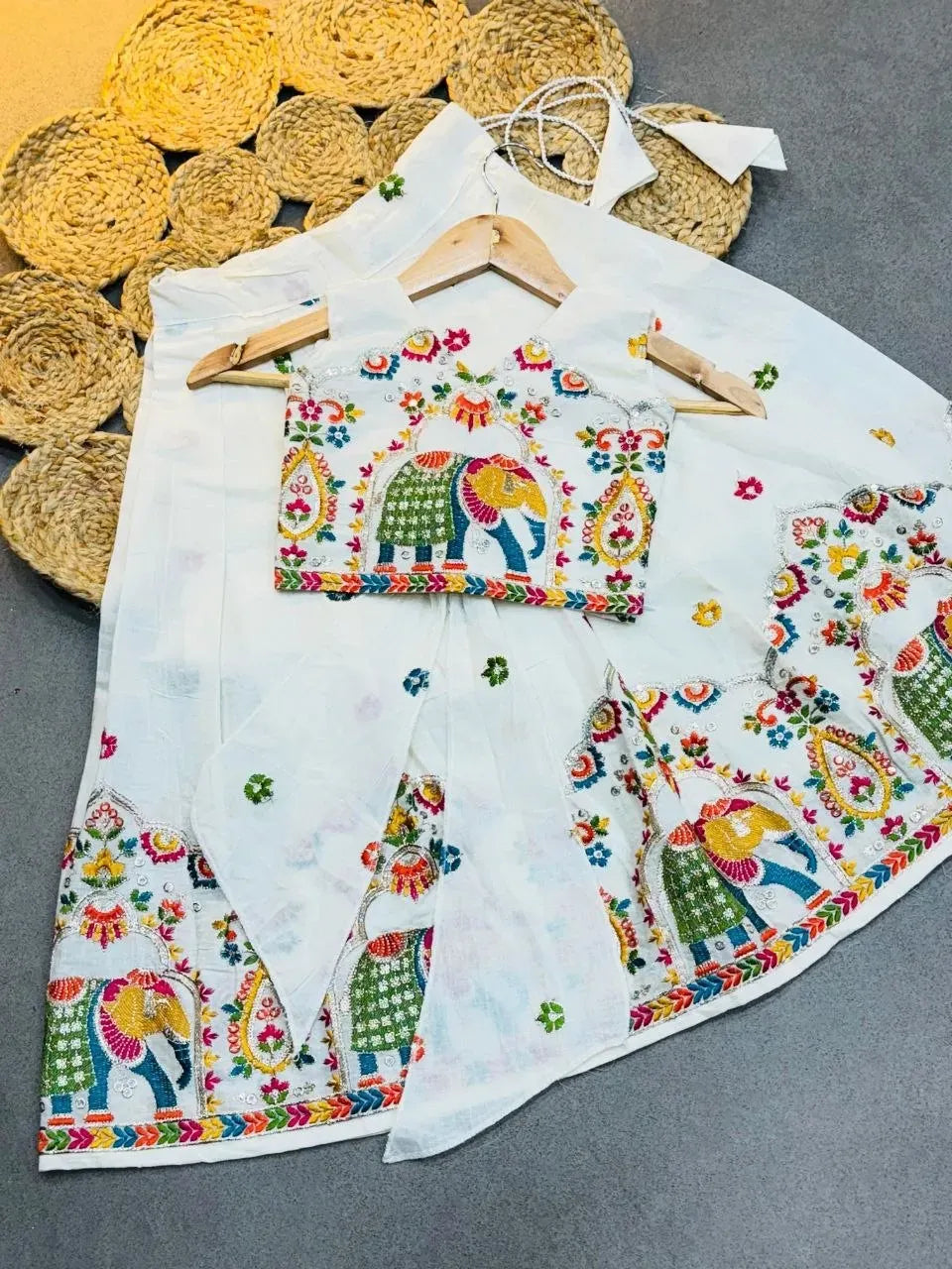 White kora cotton kids lehenga choli with multicolored elephant and floral embroidery on a textured background