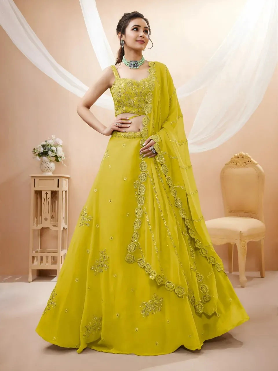 Model wearing lime yellow georgette lehenga choli with strappy blouse and dupatta