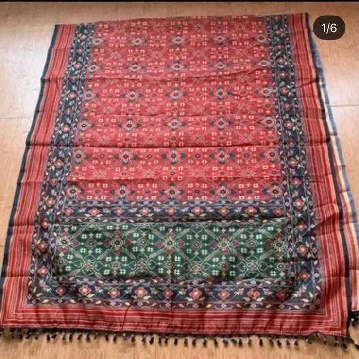 Full view of red and black patterned linen saree laid flat on wooden floor