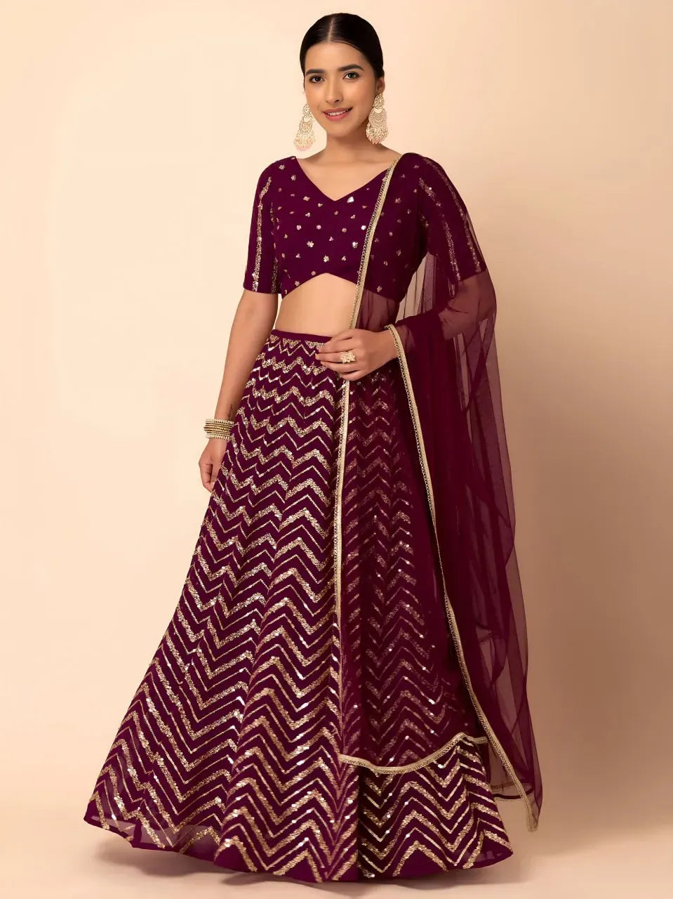 Model wearing royal maroon chevron sequin lehenga choli with net dupatta front view