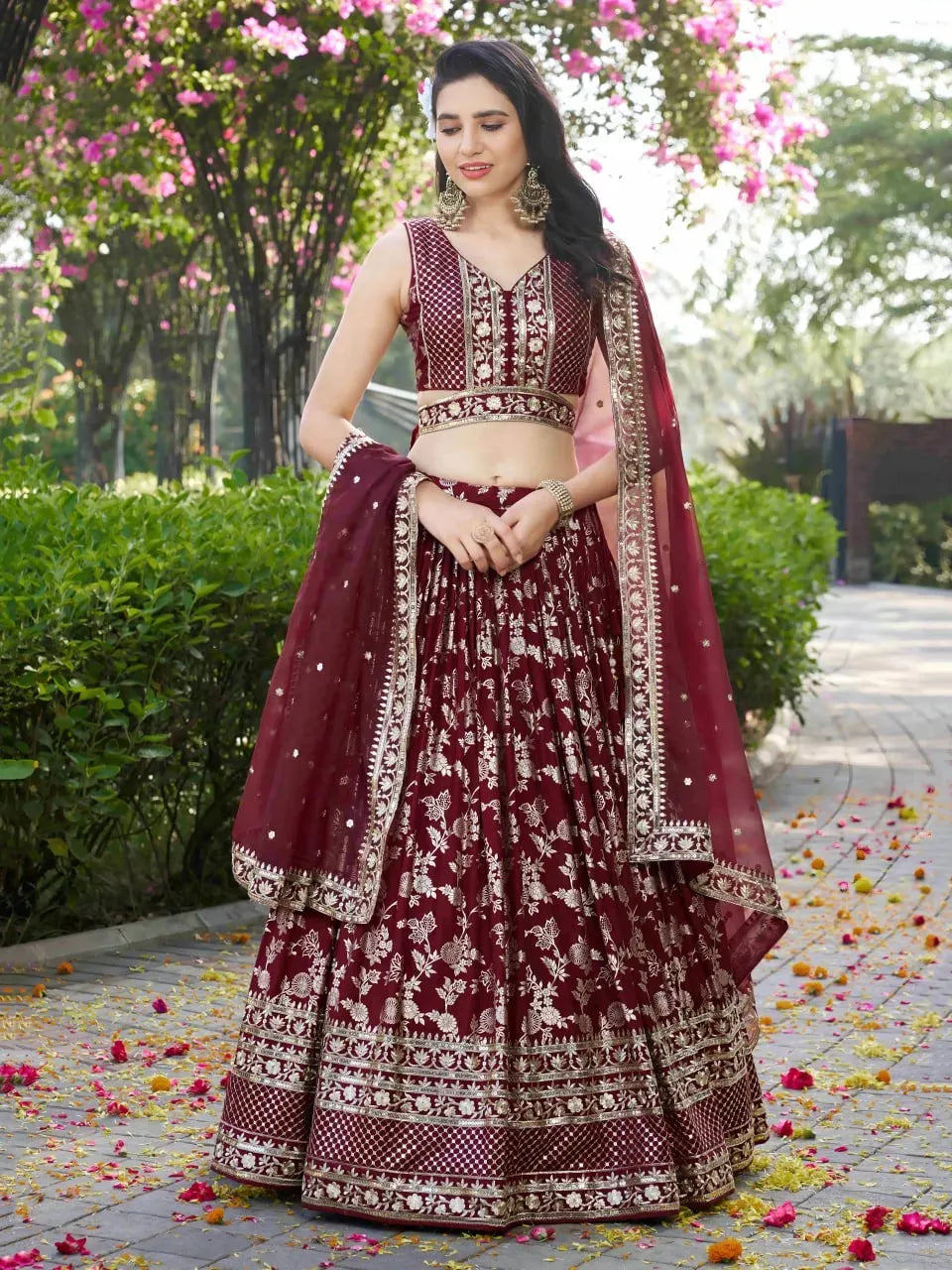 Model wearing maroon dola silk jacquard lehenga choli with zari work in garden