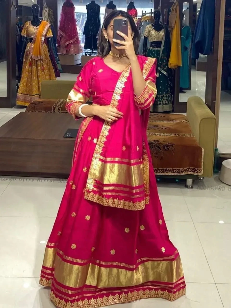 Woman wearing vibrant pink modal gajji silk lehenga set with gold gota work in a boutique