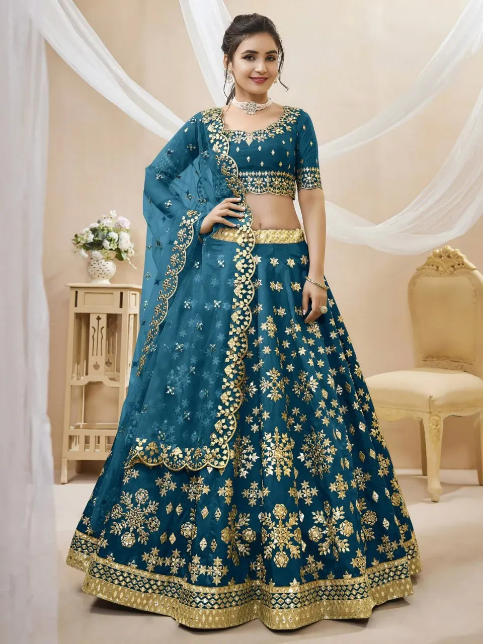 Model wearing peacock blue flared lehenga with golden floral motifs and net dupatta