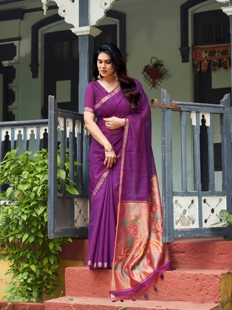 Model wearing purple pure silk saree with zari weaving on porch steps