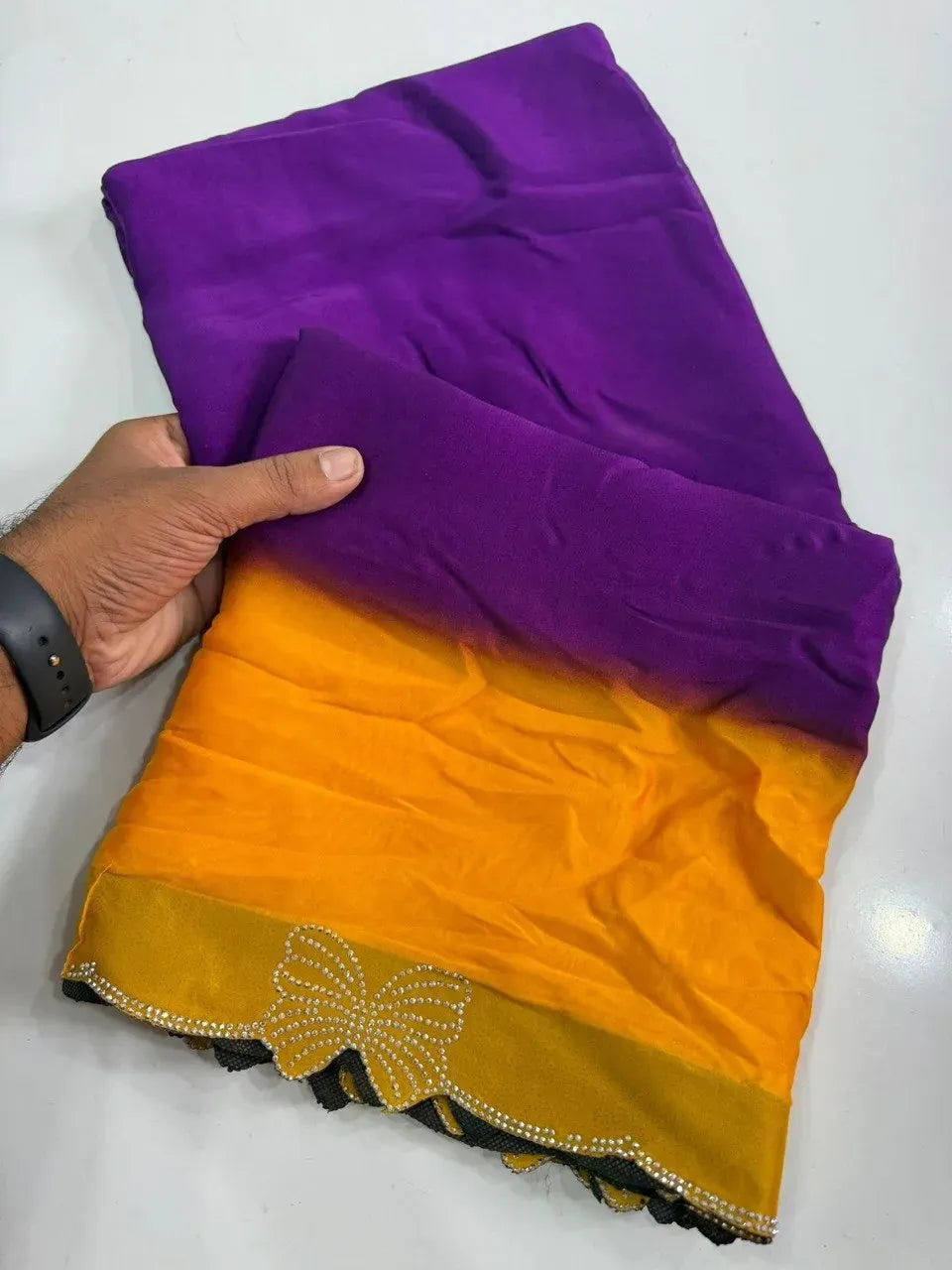 Purple and yellow gradient rangoli silk saree folded on white surface