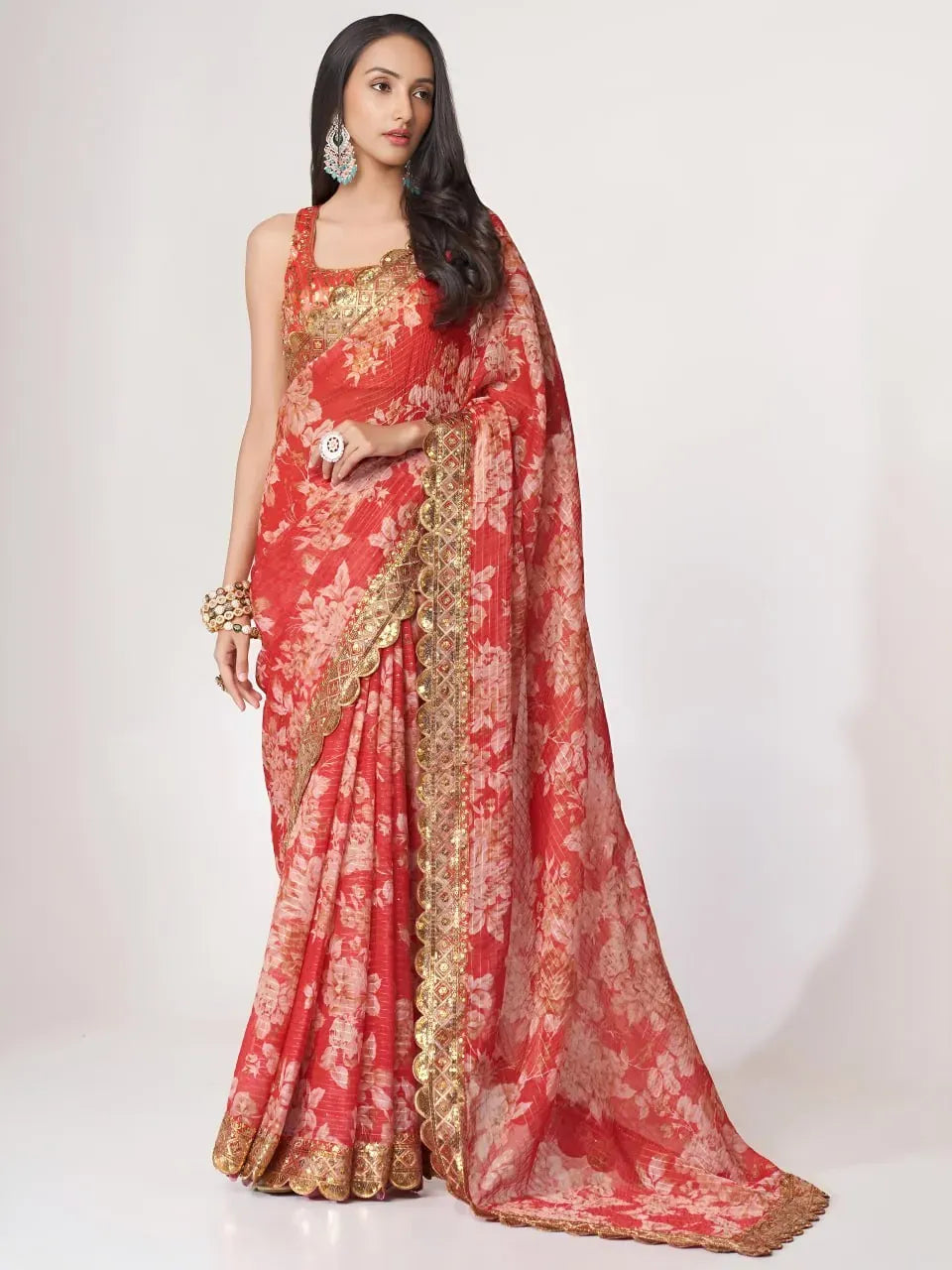 Model wearing coral red floral organza saree with gold embroidered border front view