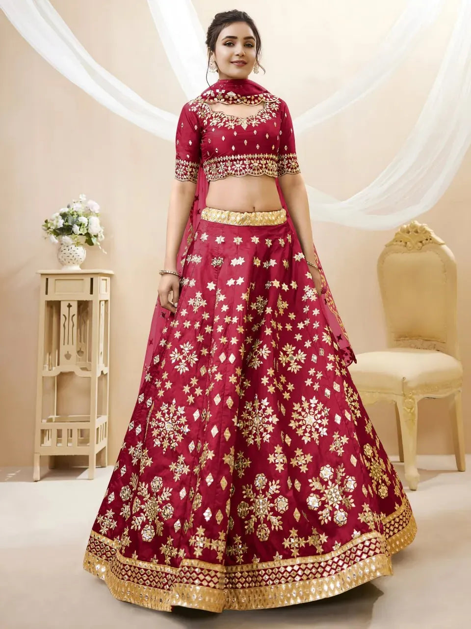 Front view of model standing in traditional red and gold lehenga set
