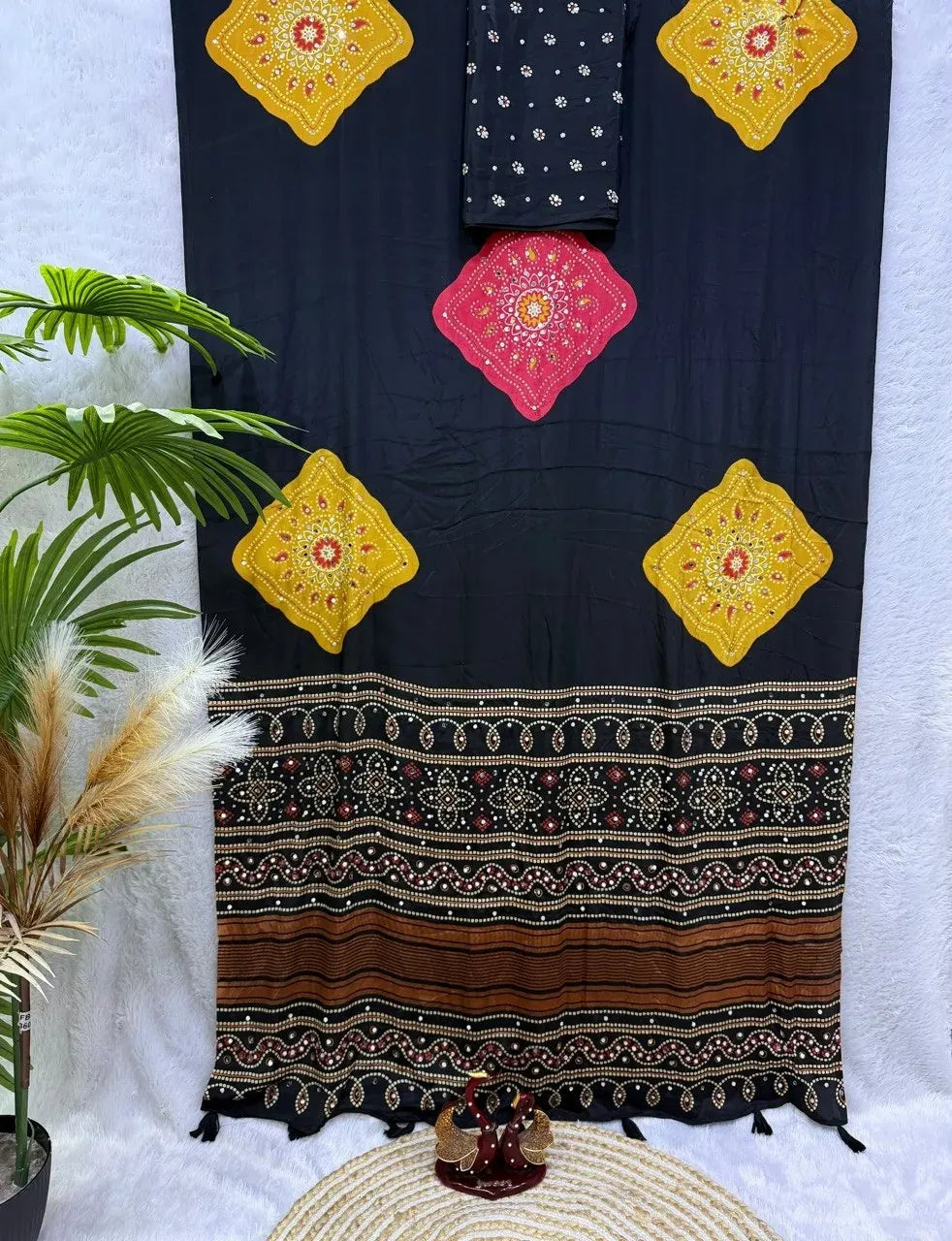 Black soft satin crepe saree with Ajrakh print and mirror work laid flat