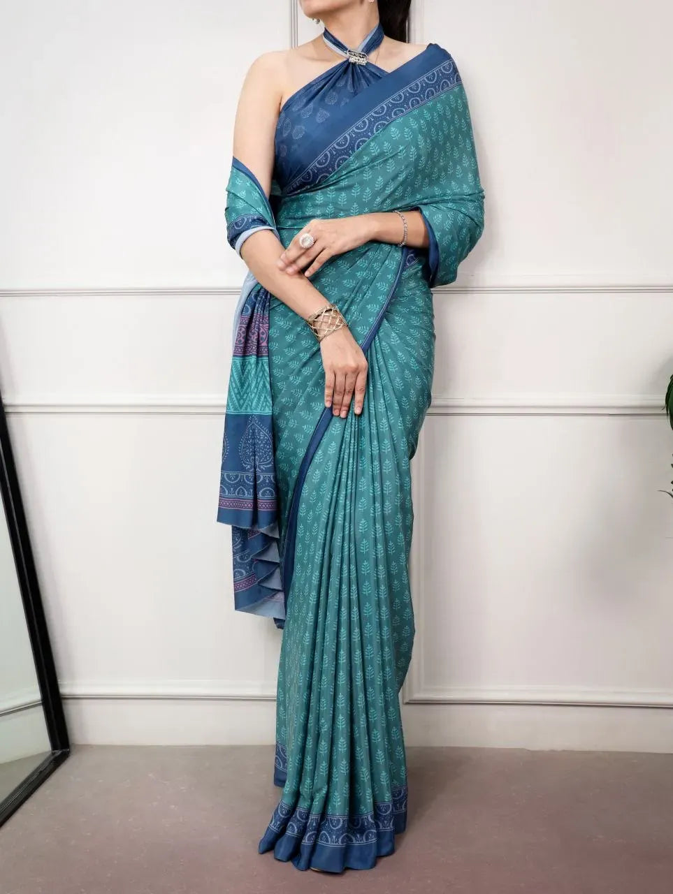 Model wearing teal green printed satin silk saree with halter neck blouse
