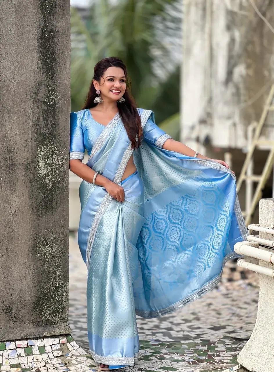Model wearing light blue tissue silk saree with silver border outdoors