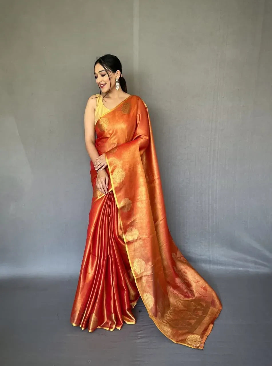 Model wearing orange tissue silk saree with gold zari weaving front facing