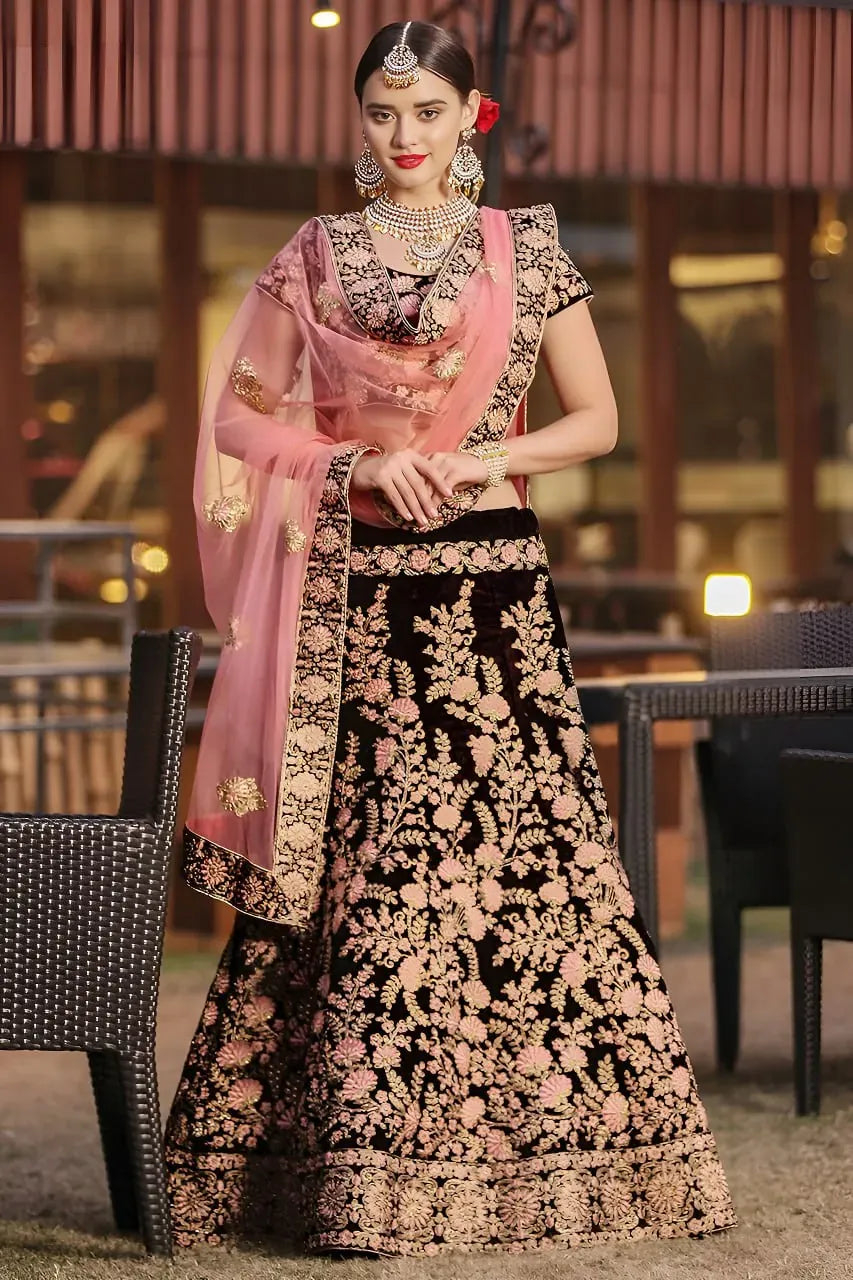 Model wearing deep maroon velvet lehenga with pink floral embroidery and pink dupatta