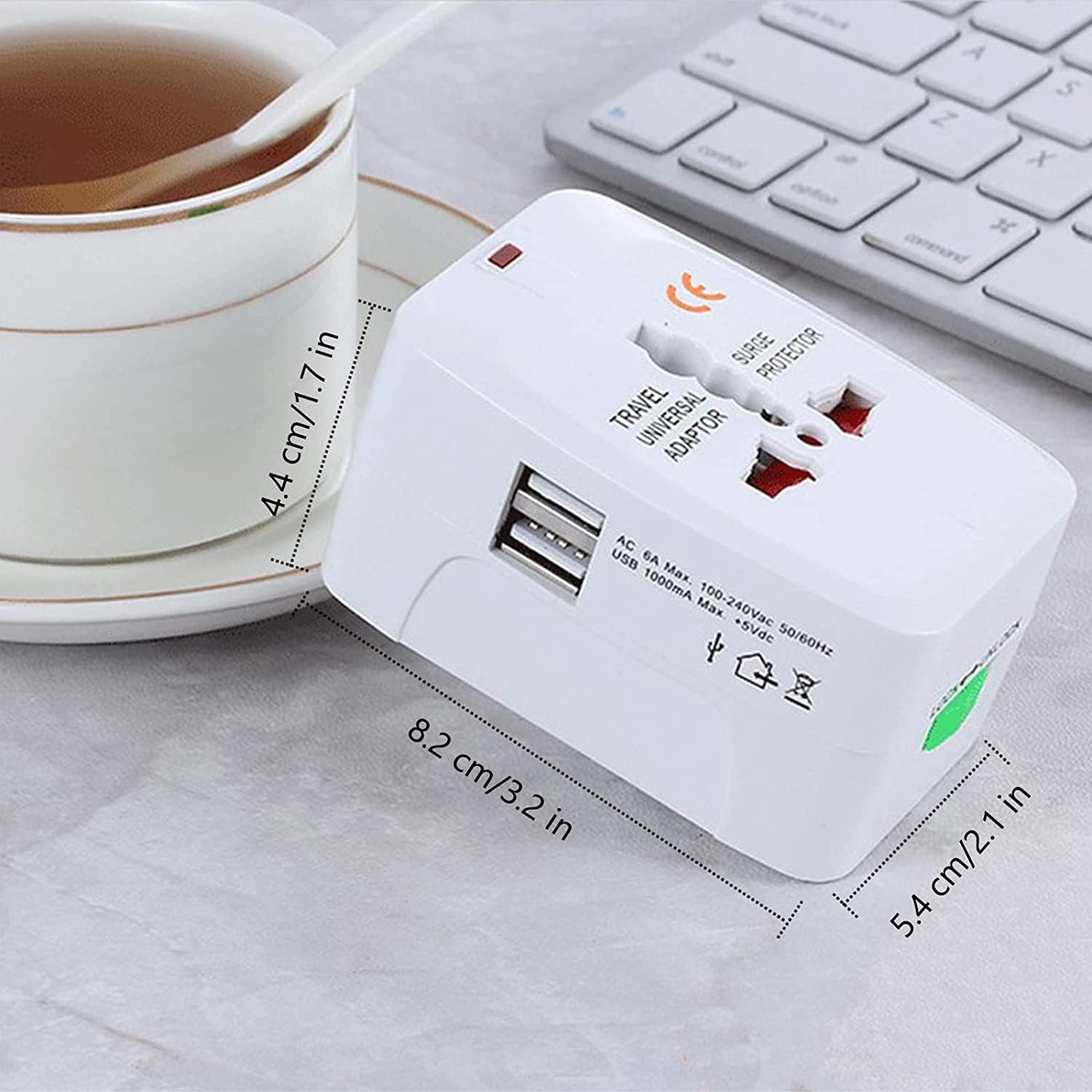 Travel adapter with USB port on a surface with a cup of tea and keyboard in the background