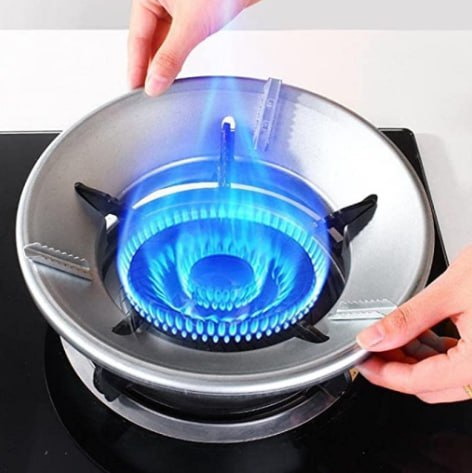 Gas stove burner with blue flame being ignited by a lighter