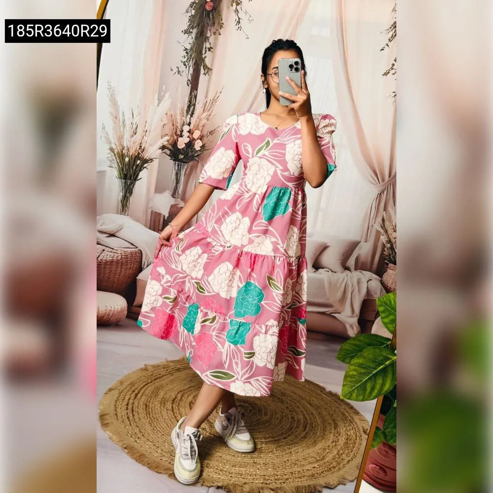 Woman in pink floral tiered cotton dress, front view, holding phone.