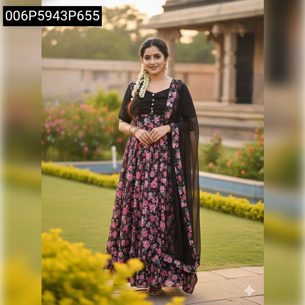 Woman posing gracefully in a black floral Anarkali suit with pink flowers and a matching dupatta, set in a lush garden.
