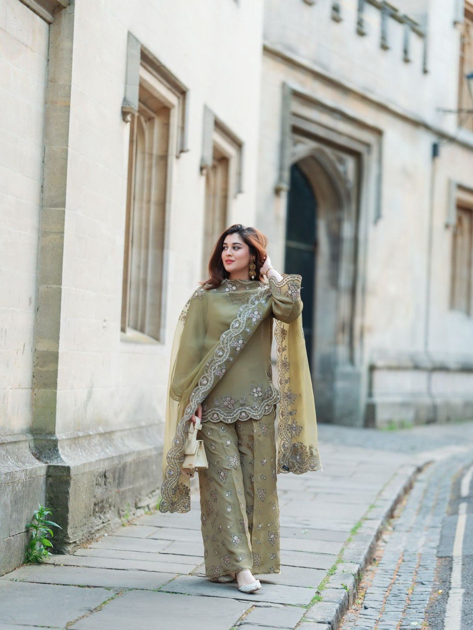 TRENDBUY woman in olive green French Crepe Silk embroidered sharara suit walking on a street
