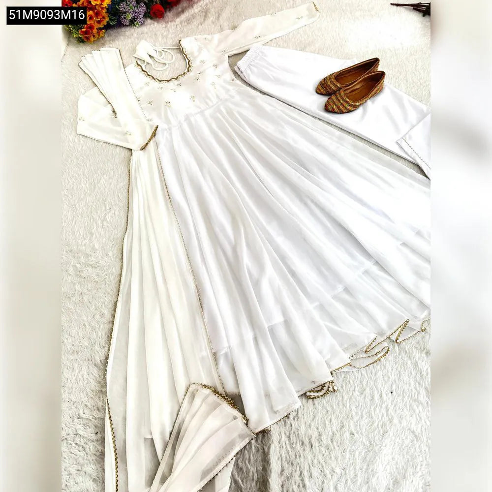 Full white Georgette Anarkali gown set with golden mirror embroidery, pant, and dupatta, laid flat on a white furry rug.