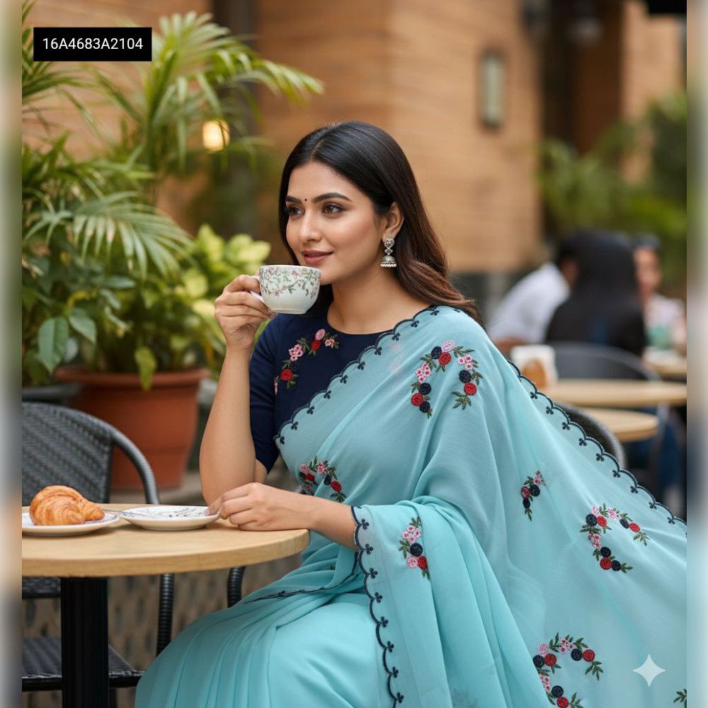 Model wearing Aqua Blue Georgette saree with floral embroidery and dark blue blouse, sitting at a cafe
