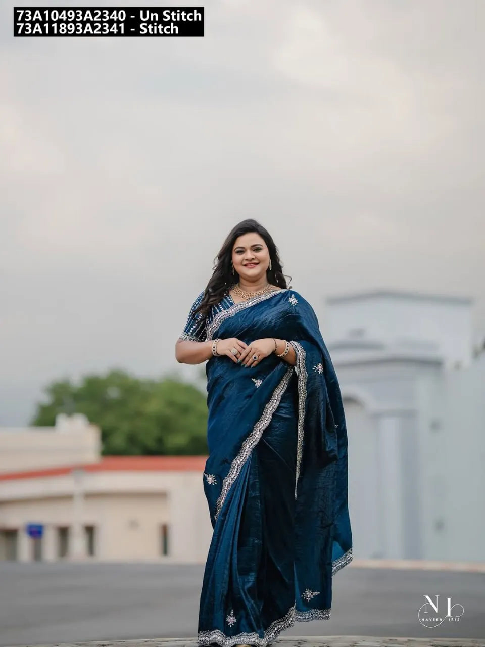 Full body shot of a smiling model wearing a stunning teal gold crush sequin saree, walking outdoors with a classic building background.